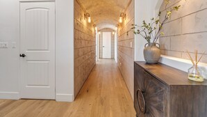 A hallway with wooden flooring, white doors, and a stone archway.
