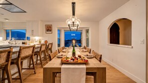 Ein Essbereich mit einem langen Holztisch, der für eine Mahlzeit gedeckt ist, umgeben von Holzstühlen.