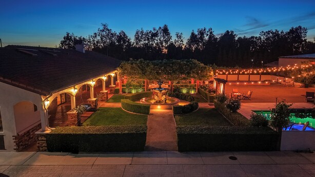 A courtyard with a fountain, seating areas, and string lights.