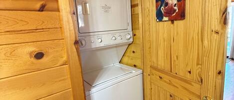 Una lavanderia funzionale con lavatrice e asciugatrice, pareti in legno e una porta decorata con un dipinto di una mucca.