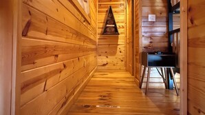 Un pasillo interior de madera con un reloj y una pequeña mesa también con un reloj.