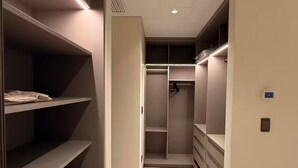 A modern walk-in closet with built-in shelving and lighting, marble flooring, and a ceiling vent.