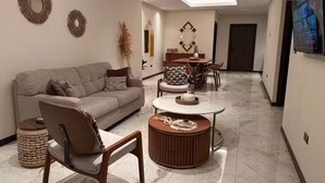 A modern living room with a sofa, chairs, a coffee table, and a dining area.