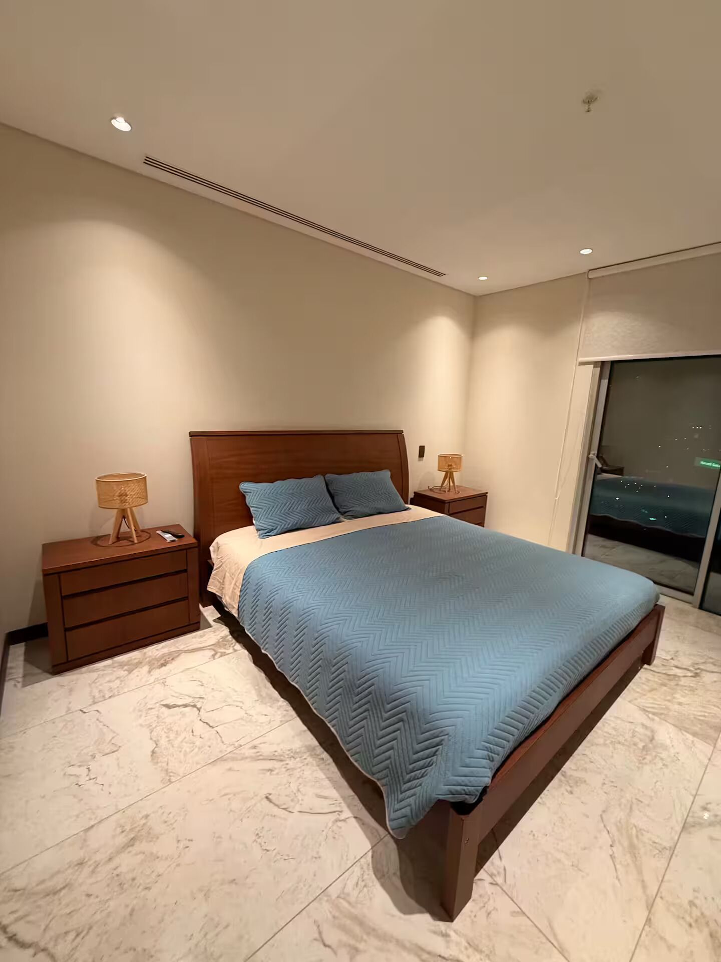 Ein modernes Schlafzimmer mit einem großen Bett, einem Holzkopfende und Marmorböden.