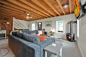 A living room with a fireplace, a sofa, a dining area, and a staircase.