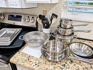 A kitchen with stainless steel cookware, a digital clock, and a granite countertop. - Pelican’s Point – Weeki Wachee Main River Home with Gulf Access (Weeki Wachee)