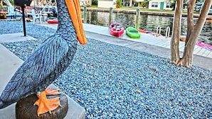A large bird sculpture, possibly a pelican, on a dock with a pebbled surface. - Pelican’s Point – Weeki Wachee Main River Home with Gulf Access (Weeki Wachee)