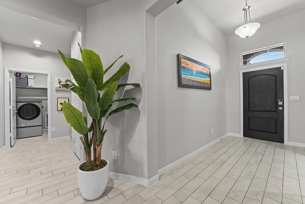 A modern interior with a potted plant, a painting, and a door. - Luxury 3BR House near Airport in Midland TX (Midland)