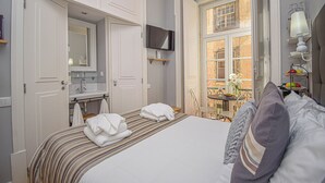 Een hotelkamer met een bed, een televisie, een badkamer met spiegel en een raam met uitzicht.