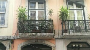 Een gebouw met een groene dubbele deur, een balkon met potplanten en het cijfer 124 aan de rechterkant.