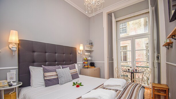 Een netjes opgemaakt slaapkamer met een groot bed, bedlampen, een klein tafeltje en een raam met uitzicht.