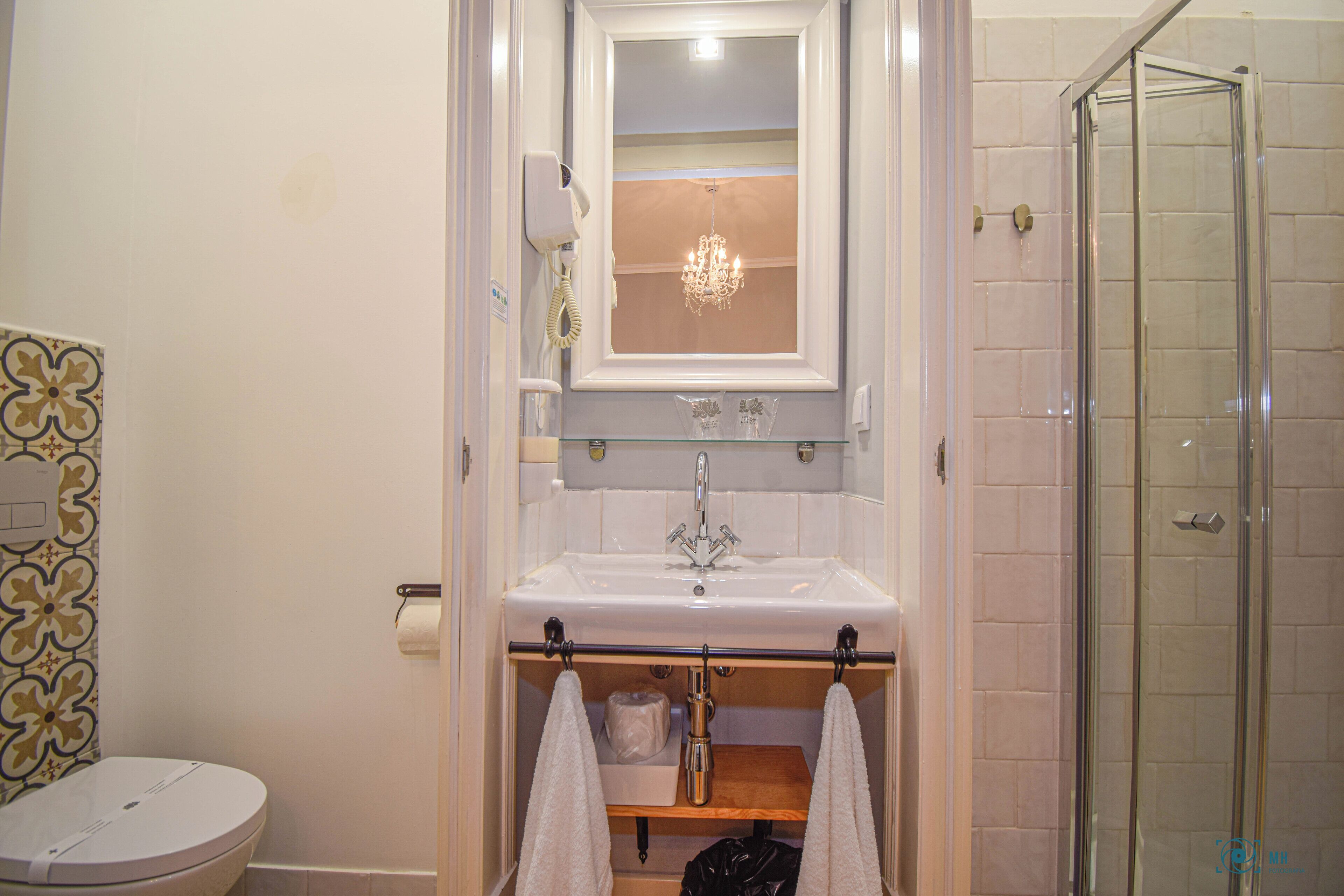 Een badkamer met een wit wastafel, een douchecabine van glas en een toilet.