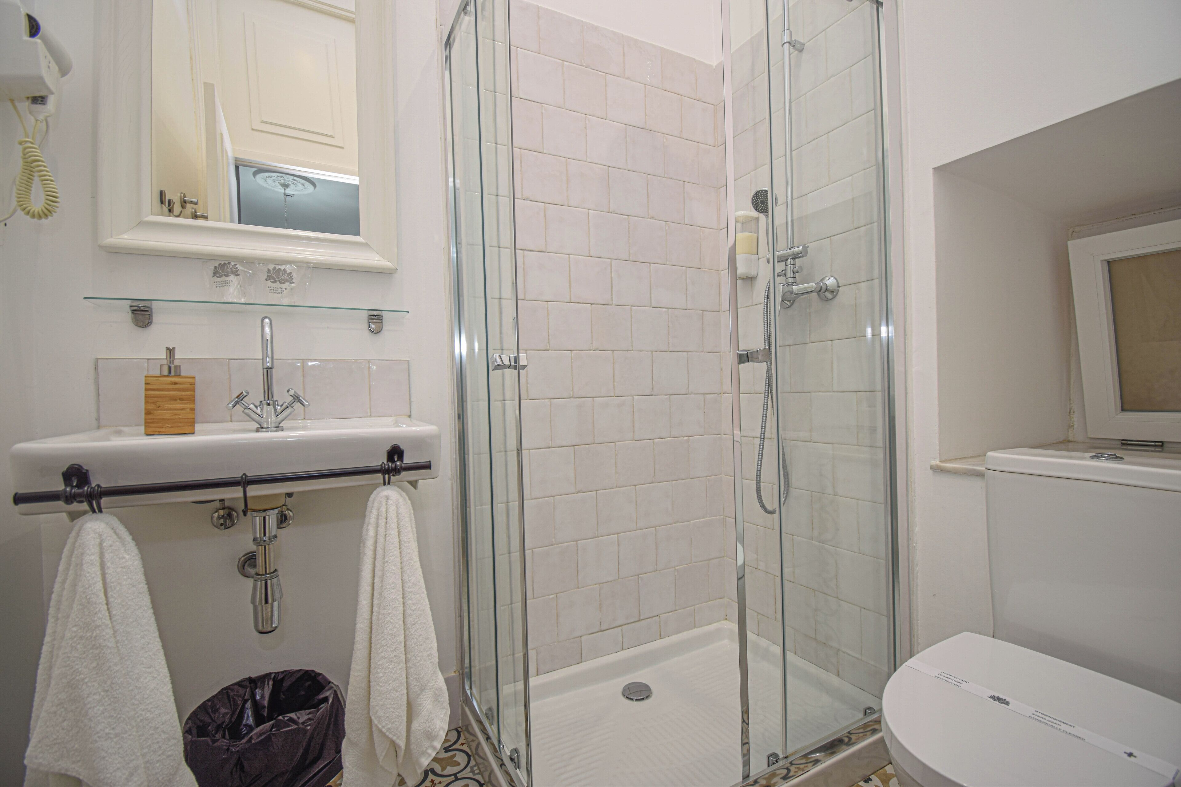 Un baño moderno con ducha de vidrio, lavamanos blanco y un inodoro.