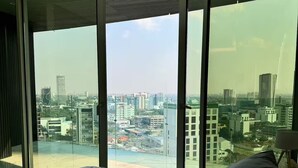 Quarto com uma cama grande, vista para a cidade através de janelas do chão ao teto e design de interiores moderno.