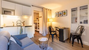 A compact living space with a kitchenette, a dining area, and a sofa. - Le Cocon Douillet - Proche Télécabines (Les Angles)