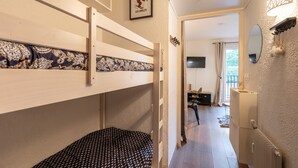 A bunk bed room with a patterned headboard, a small desk with a chair, a mirror, and a radiator. - Le Cocon Douillet - Proche Télécabines (Les Angles)