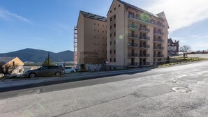 A multi-story building with balconies, labeled "SOLARIUM," located near a road with parked cars. - Le Cocon Douillet - Proche Télécabines (Les Angles)