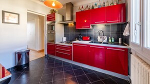Una cocina moderna con armarios rojos, baldosas negras, una campana extractora de acero inoxidable y una ventana con vistas.