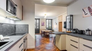 Eine moderne Küche mit einer zentralen Kochinsel, integrierten Geräten und einem Essbereich mit Holztisch und -stühlen.