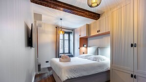 Ein modernes Schlafzimmer mit einem großen Bett, Holzboden, Einbauschrank und einer Deckenleuchte.