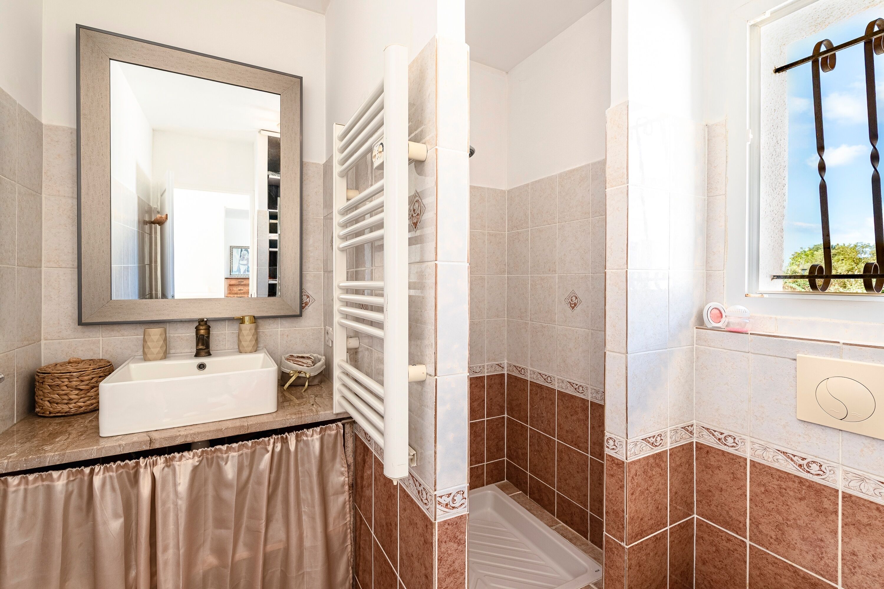 A bathroom with a white sink, a mirror, a towel rack, and a shower area.