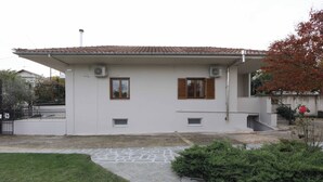Ein einstöckiges Haus mit Ziegeldach, zwei Fenstern mit Fensterläden und einer kleinen Veranda.