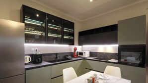 Eine moderne Küche mit Essbereich, ausgestattet mit einer integrierten Mikrowelle, einer Kaffeemaschine und einer Glastrennwand.