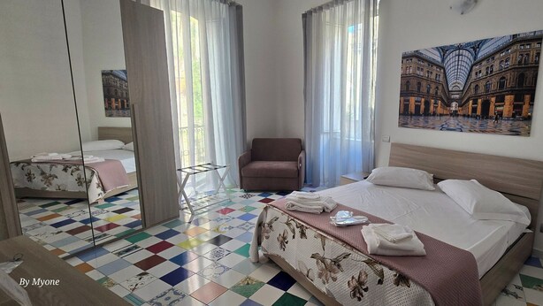 Une chambre d’hôtel avec un grand lit, une chaise, une petite table et un miroir.