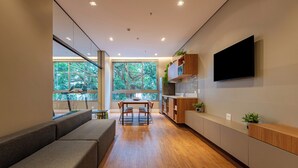 Una cucina moderna con pavimento in legno, un'area pranzo con tavolo e sedie e un televisore integrato nel muro.