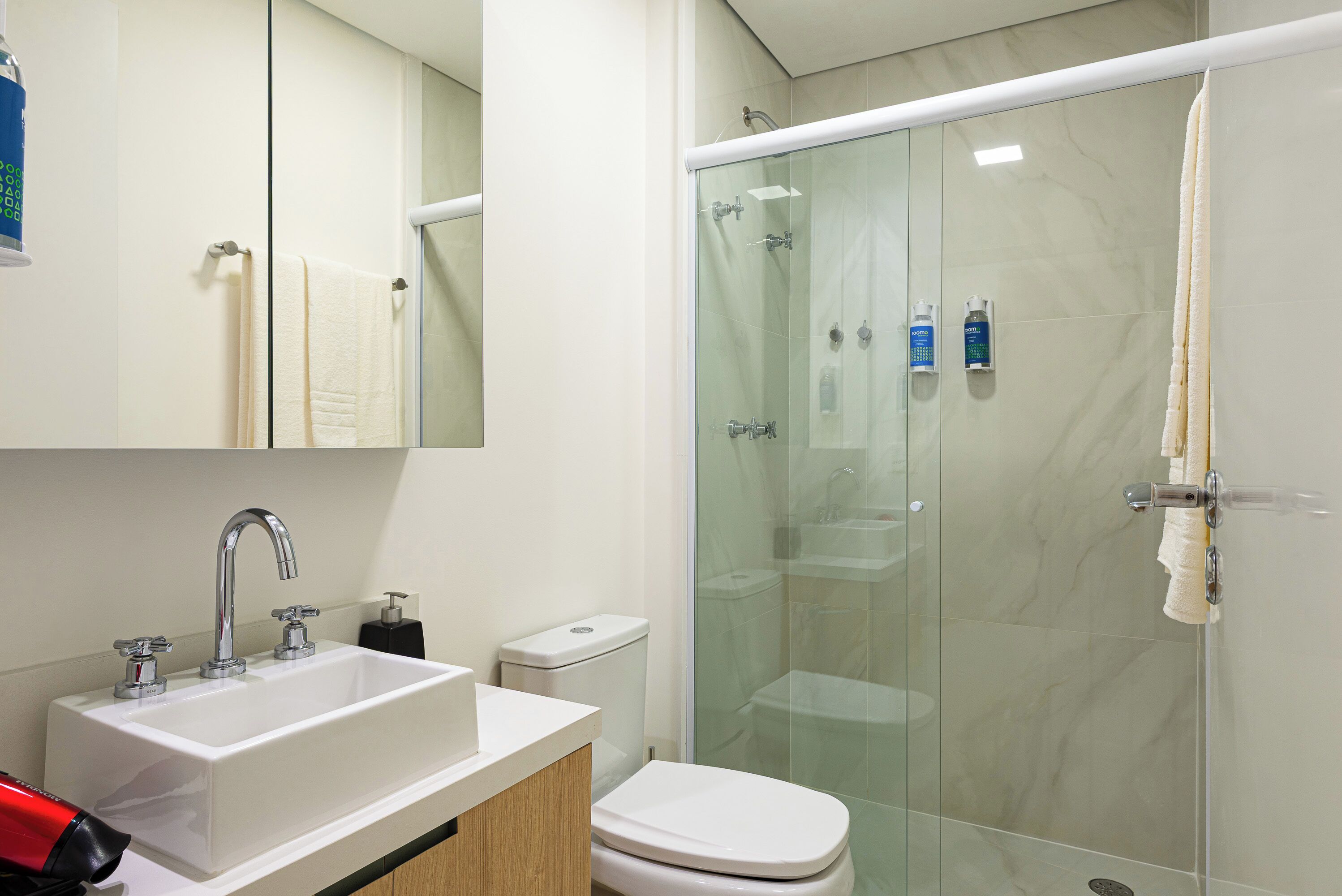 Une salle de bain moderne avec une douche à parois de verre, un lavabo blanc et des toilettes.