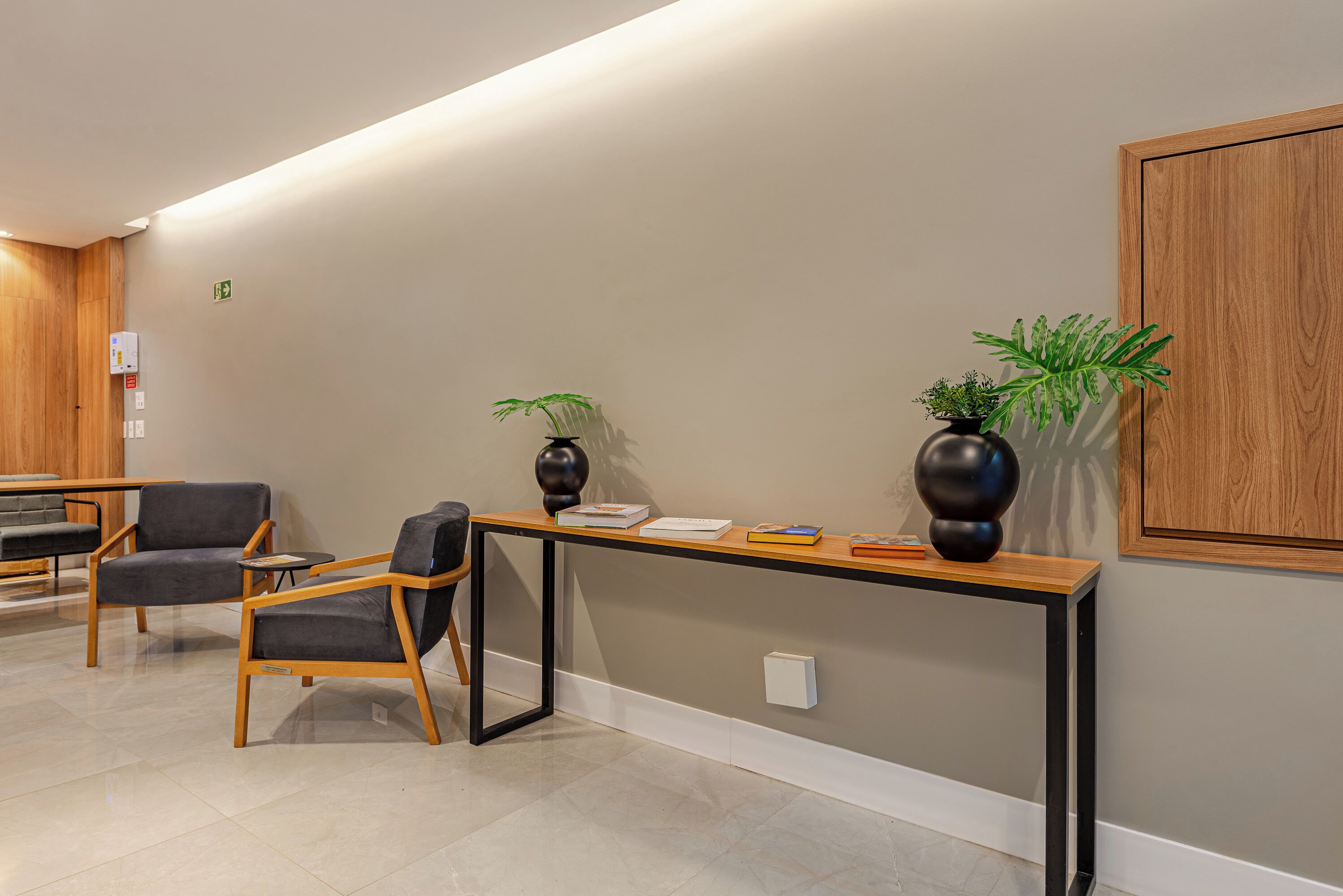 A reception area with a wooden desk, two chairs, a potted plant, and a wooden cabinet.