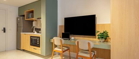 A modern kitchen with a built-in oven, a refrigerator, and a dining area with two chairs and a table.
