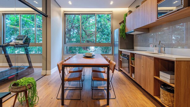 Una cucina moderna con una grande finestra, mobili in legno e un'area pranzo con tavolo e sedie.