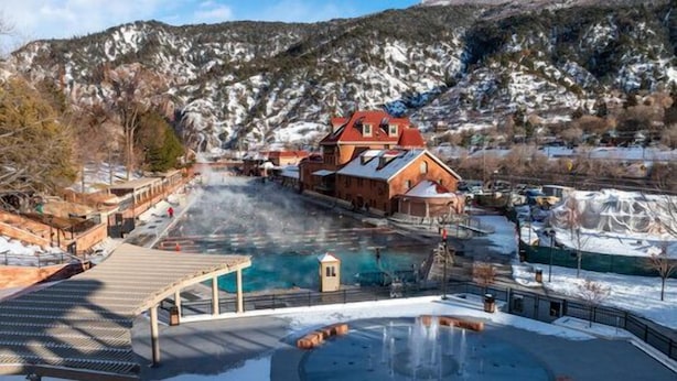 A spa area with a hot tub, wooden deck, and a building with a red roof.