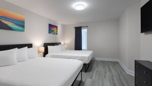 Hotellihuone, jossa on kaksi sänkyä, taulutelevisio, lipasto ja taideteoksia seinillä.