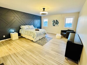 A modern bedroom with a bed, bedside tables, a TV, and a large window.