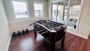 Una habitación con mesa de fútbol, ventanas y vistas a un paisaje nevado.