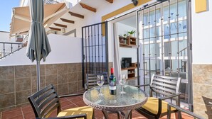 A patio with a round table, chairs, and a bottle of wine. - Casa José: Mountain Views, Wi-Fi, and Air Conditioning in Nerja (Nerja)