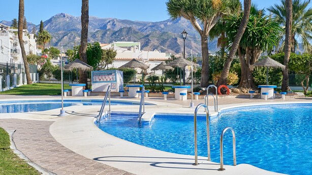 A swimming pool with multiple lanes, palm trees, and a mountainous backdrop. - Casa José: Mountain Views, Wi-Fi, and Air Conditioning in Nerja (Nerja)
