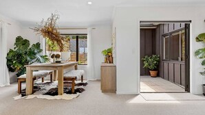 A modern interior with a wooden dining table, a cowhide rug, and large green plants. - Rangatira Sunsets & Close to town (Taupō)