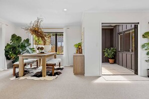 Un interior moderno con una mesa de comedor de madera, un tapiz de cuero de vaca y plantas verdes grandes.