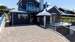 A modern two-story house with a balcony, large windows, and a tiled patio. - Rangatira Sunsets & Close to town (Taupō)
