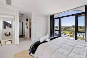Un dormitorio con una cama grande, vistas al campo y una puerta que da a otra habitación.