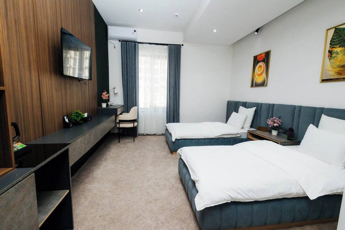 Een moderne hotelkamer met twee bedden, een bureau, een stoel en een televisie.