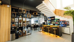 A modern bar area with a staircase, shelves with various items, and a seating area with bar stools. - Zafar Plaza Hotel (Namangan)