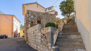 A narrow street with stone steps leading to a building with a stone facade and a small arched window.