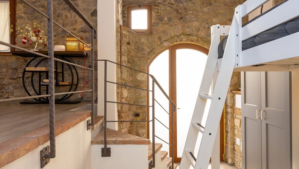 A staircase with a metal railing, a wooden platform, and a stone wall.
