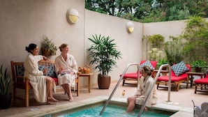 A poolside area with three people in bathrobes, a pool, lounge chairs, and potted plants. - Pet-Friendly Silverado Condos with Pool & Golf Course View (Napa)