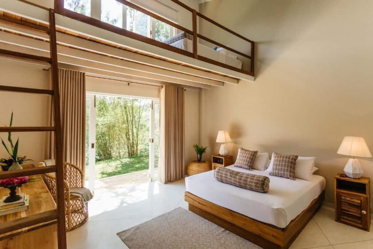 A modern bedroom with a large bed, a wooden desk, and a balcony.