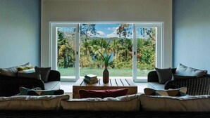 A modern living room with a large window, a sofa set, and a wooden coffee table. - Rukgala Retreat (Digana, Kandy)
